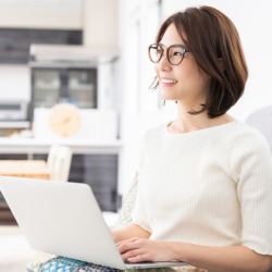 Happy woman sitting at desk using laptop | VRM Readiness Manager Housekeeping Software