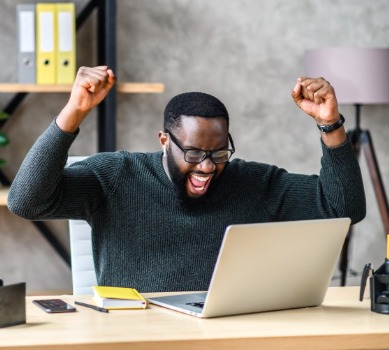 Man at desk celebrating remotely with work team  | VRM Vacation Rental Software